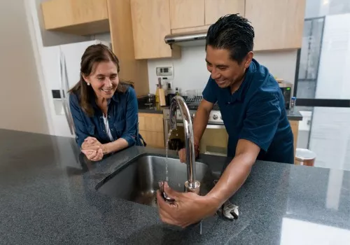 A happy plumbing contractor helping fix a sink faucet