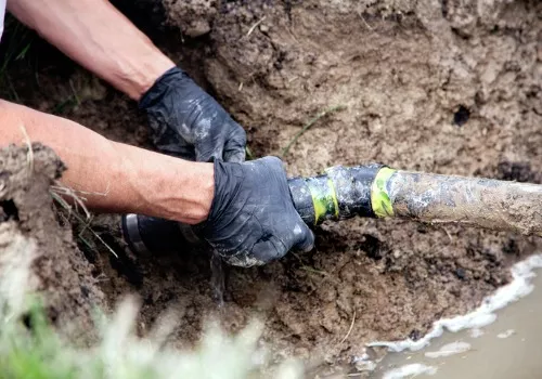 A plumber digging up and pulling out a broken pipe