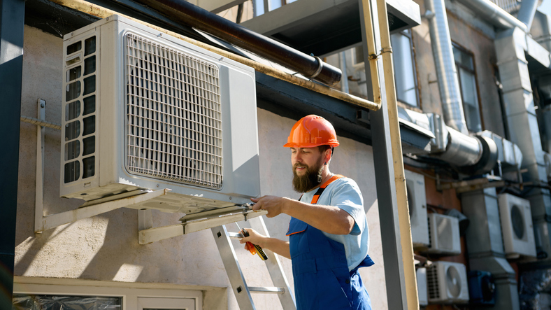 Commercial Heating and Cooling Pekin IL, Technician installing air conditioning unit outdoors. Concept of engineering services, HVAC maintenance, and workplace safety with focus and confidence.